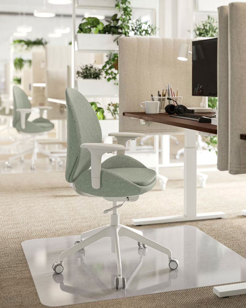 Silla de trabajo y escritorio de colores claros en un cubículo de oficina.