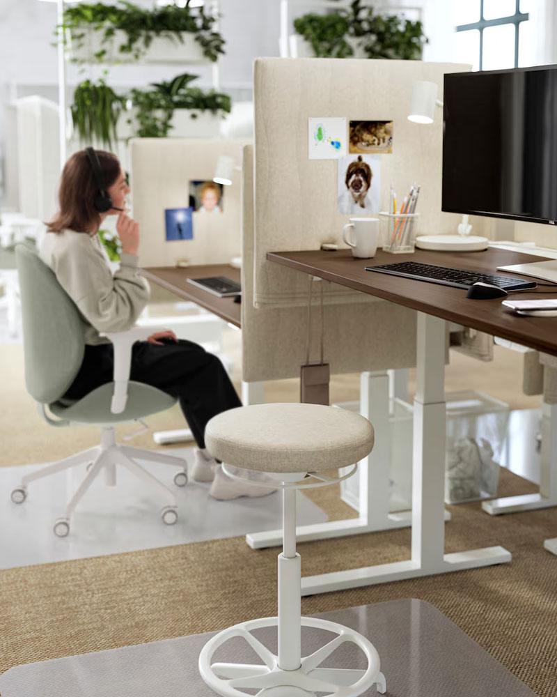 Silla de trabajo alta, en un cubículo de oficina con un ordenador, se puede ver un entorno de trabajo creativo y moderno.