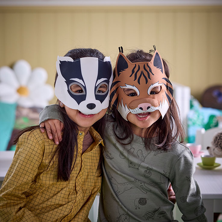 Two happy girls with badger and bobcat masks. Playful and cheerful indoor atmosphere.