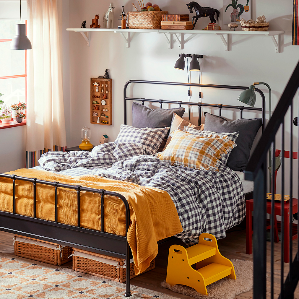 Habitación calida, con cama STJÄRNÖ y edredones de cuadros. 