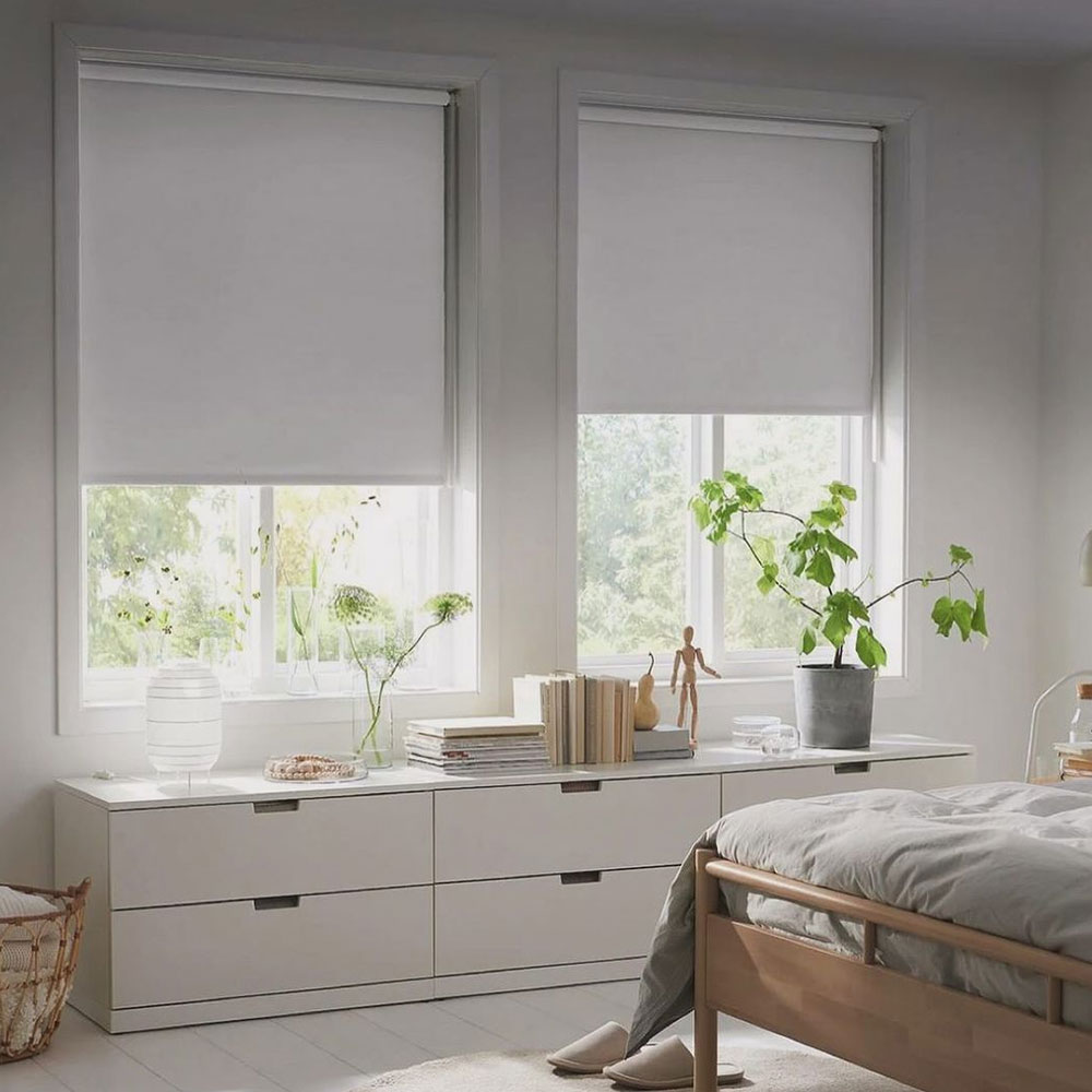 Un cuarto con estores FÖNSTERBLAD cerrados a la mitad y una cajonera NORDLI.