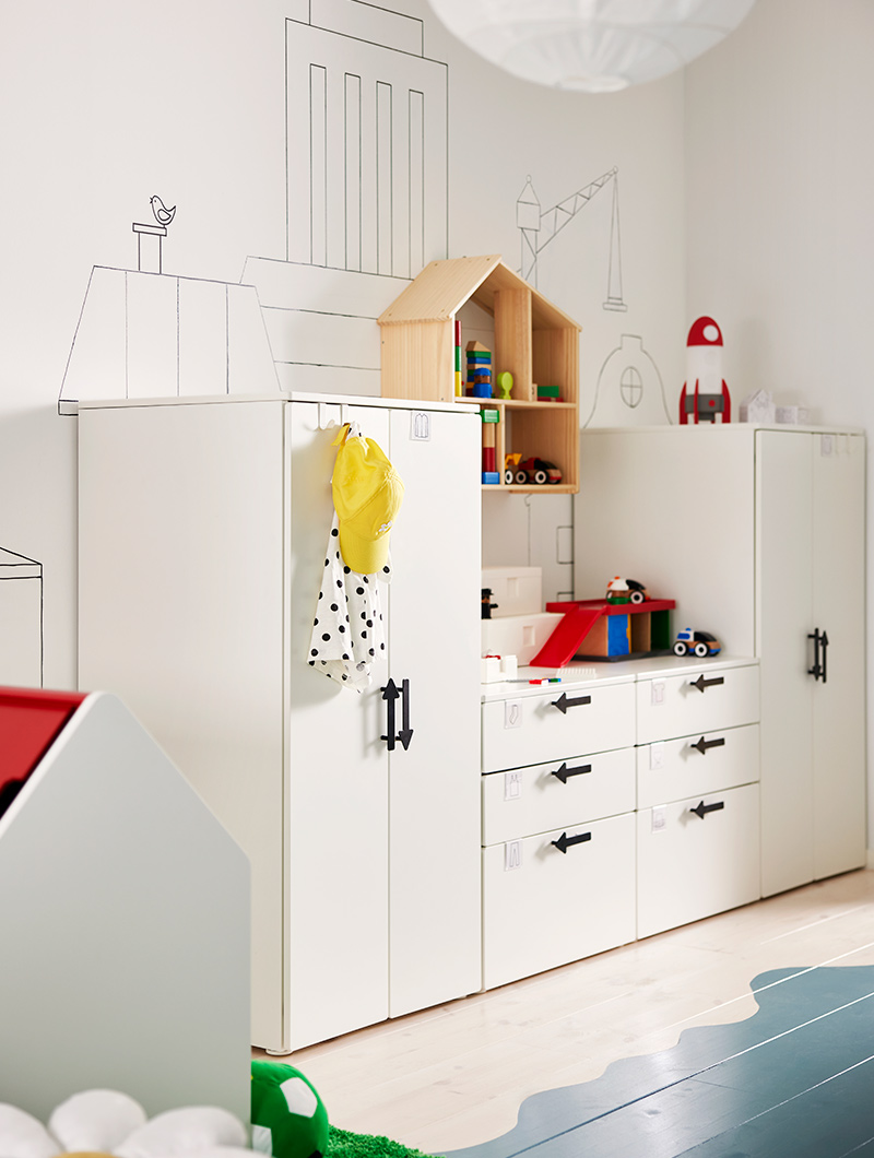 Habitación infantil con almacenamiento blanco, estante de casita de muñecas y decoración de ciudad. Ambiente organizado.