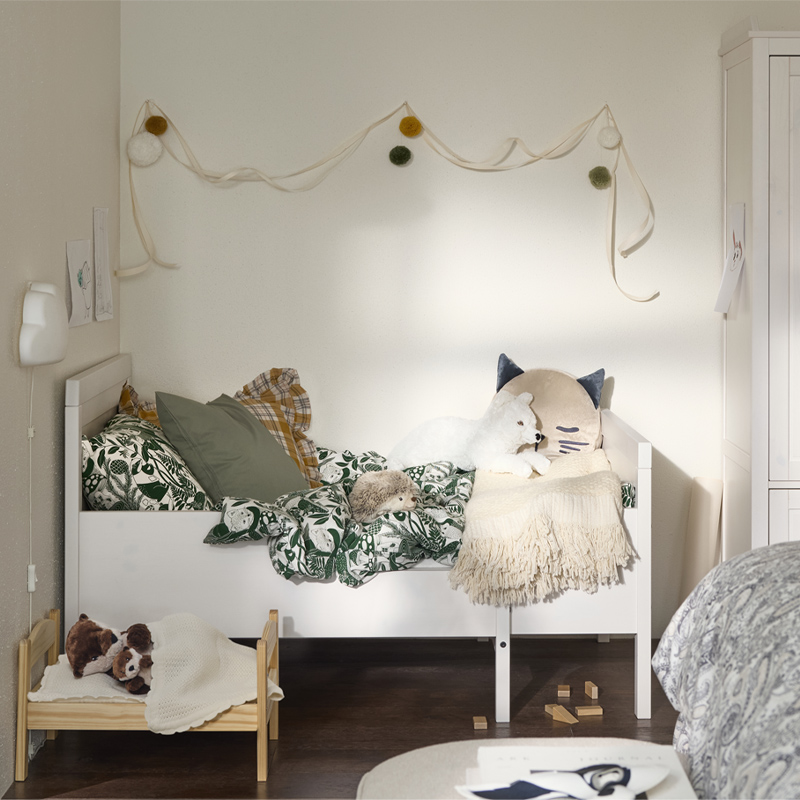 Habitación infantil acogedora con cama blanca, peluches y detalles decorativos en tonos suaves.