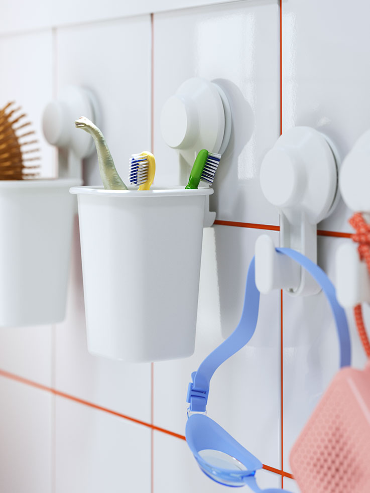  Colorful toothbrushes and blue swimming goggles hung in white tiled bathroom.