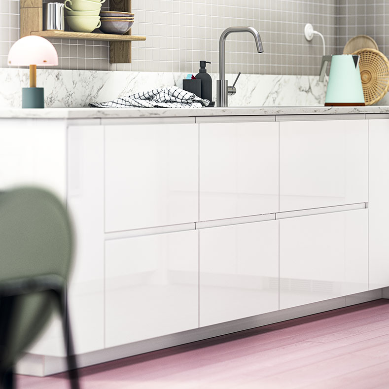 Modern kitchen with white cabinets, grey faucet, and accessories on marble countertop.