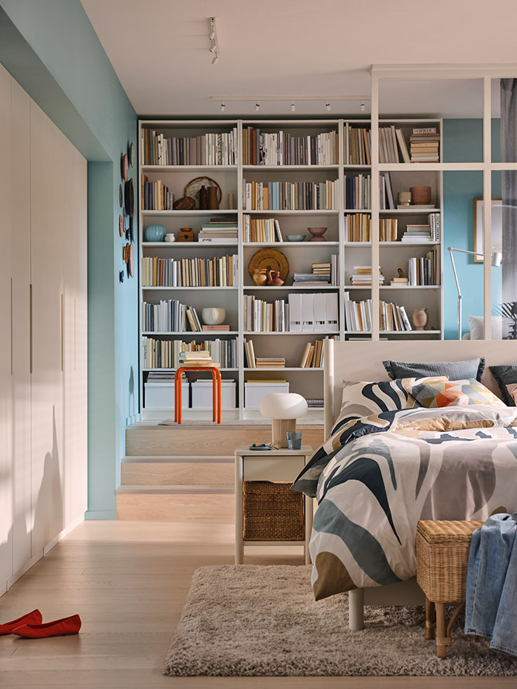 A bedroom with three BILLY bookcases in the background, a TONSTAD bed next to a TONSTAD nightstand.