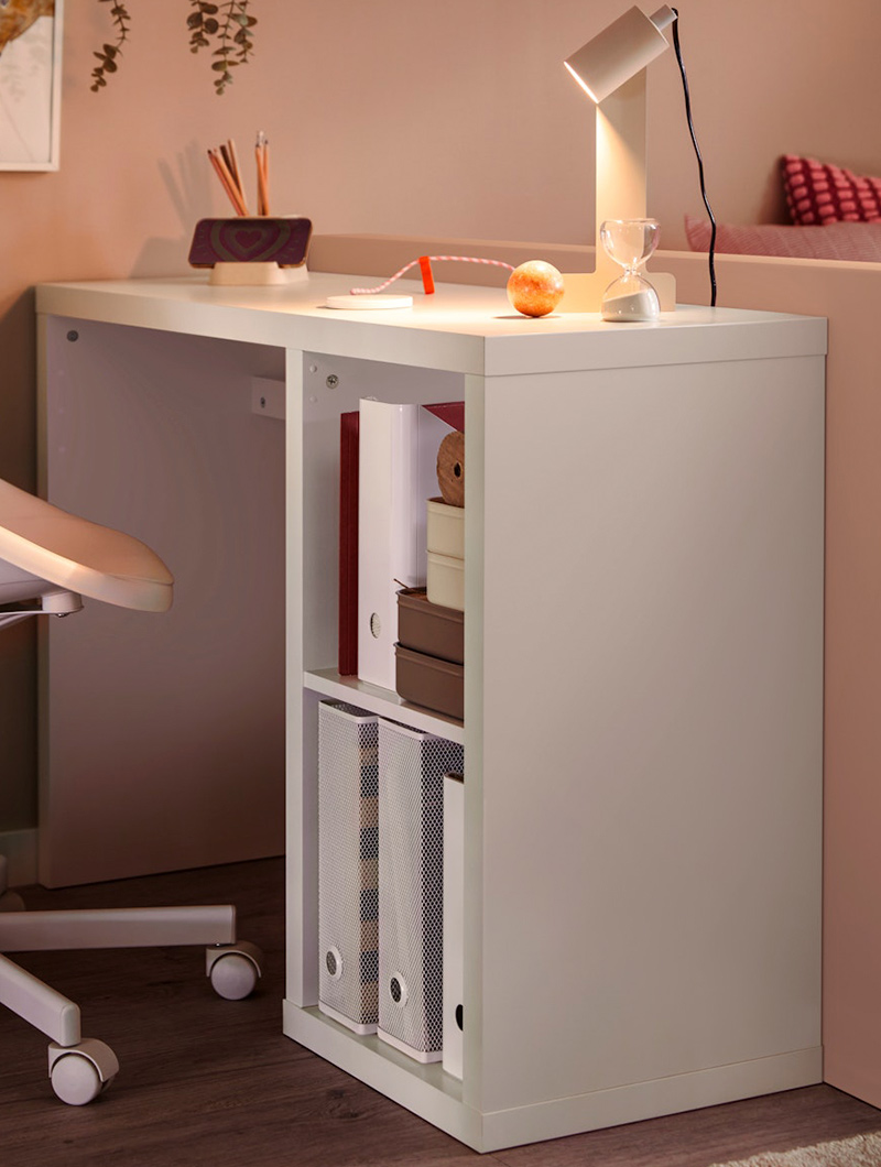 Escritorio blanco con estantería lateral, lámpara y objetos. Ambiente de estudio y trabajo.