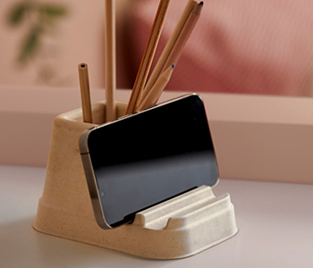 Soporte beige con lápices de madera y teléfono móvil. Ambiente de escritorio ordenado y minimalista.