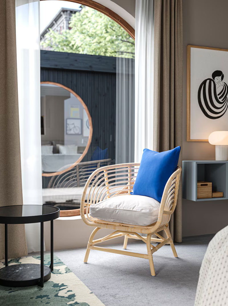 Un salón moderno, con un sillón de mimbre tejido, frente a una gran ventana, en lo que parece un dormitorio.