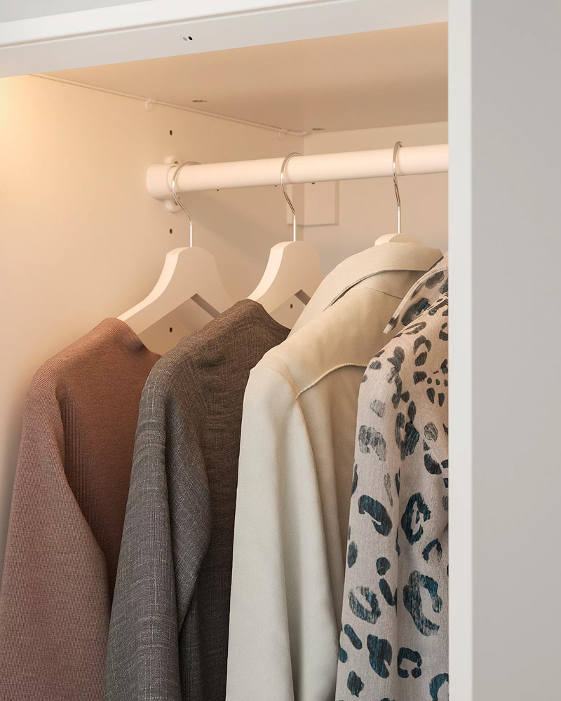An open BOAXEL wardrobe with clothes hanging on BUMERANG hangers.
