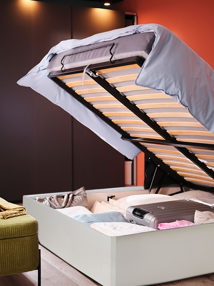 A MALM ottoman bed next to a VALTOPR storage bench in a bedroom.