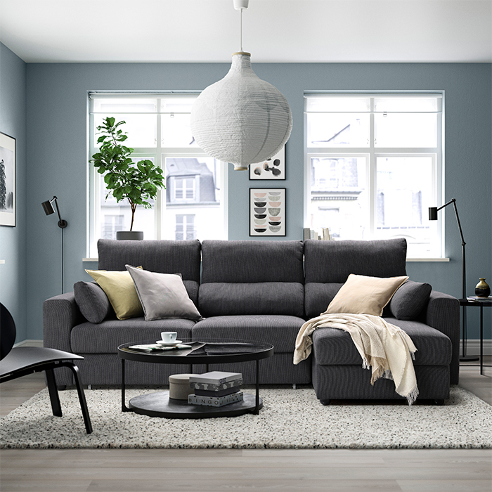 Salón luminoso con sofá chaise longue ESKILSTUNA, mesa redonda y detalles suaves y acogedores.