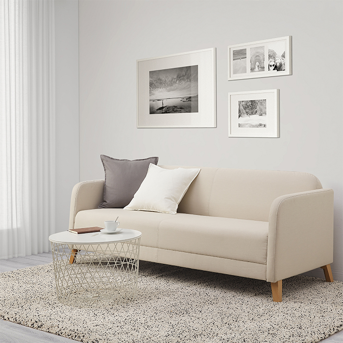A living room with a three-seat LINANÄS sofa, two DYTÅG cushions, RÖDALM frames on the wall above, and a KVISTBRO storage table in front.