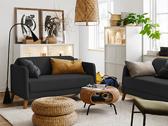 A living room with two two-seat LINANÄS sofas with cushions placed on top, two ALSEDA stools, and a GAMLEHULT storage table.