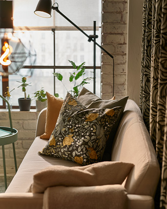 A living room with a two-seat LINANÄS sofa with two cushions on top, and a side table in the background.