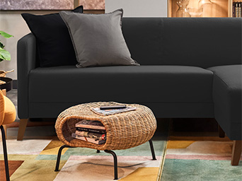 A room with a black sofa in the center and two DYTÅG cushions, and a GAMLEHULT storage table in front.