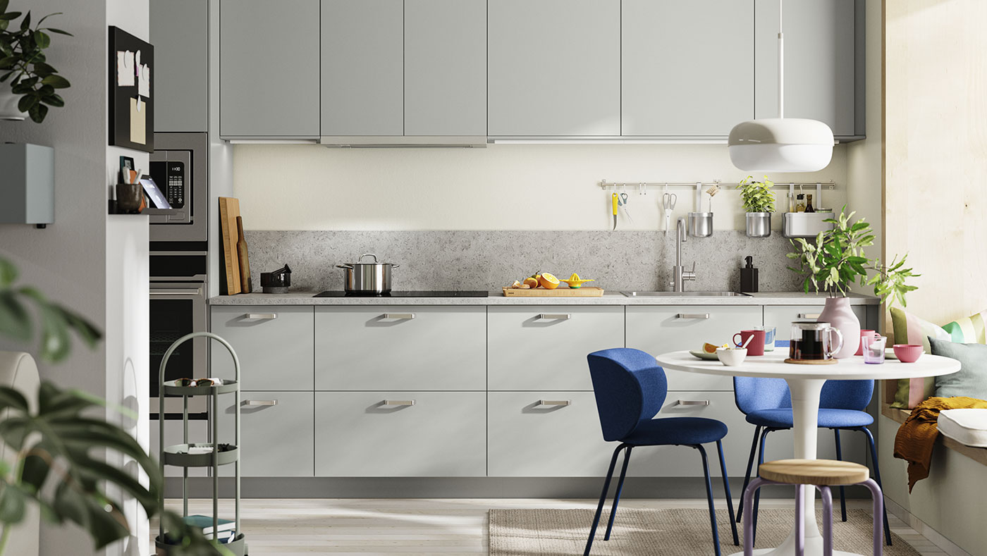 Cocina moderna gris y blanca, mesa redonda con sillas azules. Ambiente luminoso y contemporáneo.