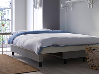 Una cama con ropa de cama blanca y azul en un dormitorio moderno y minimalista.