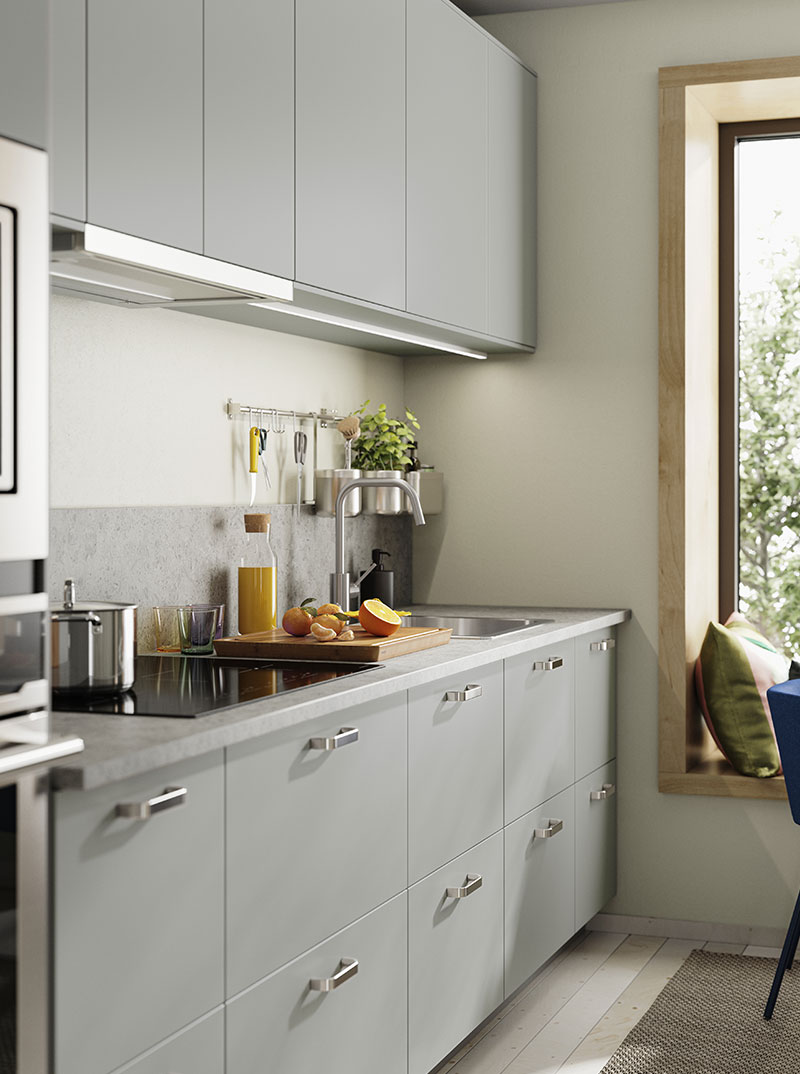 Cocina moderna con gabinetes grises, encimera clara y plantas verdes. Ambiente luminoso y acogedor.