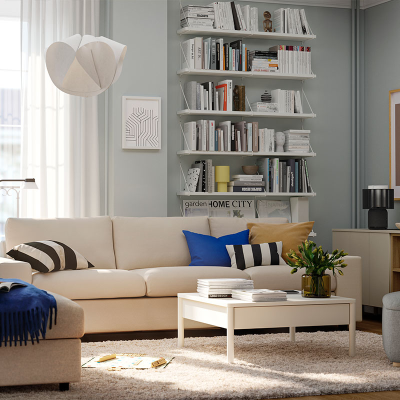 Modern living room with light sofa, bookshelves, coffee table and footrest