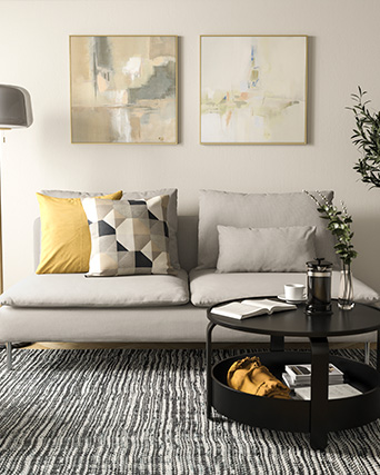 Sofá gris de estilo moderno en sala iluminada, con decoración en tonos beige, mesa de centro redonda negra.