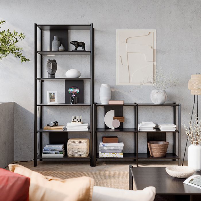 A modern living room with minimalist black shelving filled with books, vases, and decorative objects against a concrete wall.