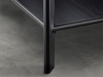 Close-up of black metal leg and lower shelf on polished concrete floor.