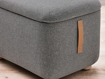 A grey upholstered stool.