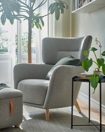 Grey upholstered armchair with headrest in a modern setting, next to a tray-style side table.