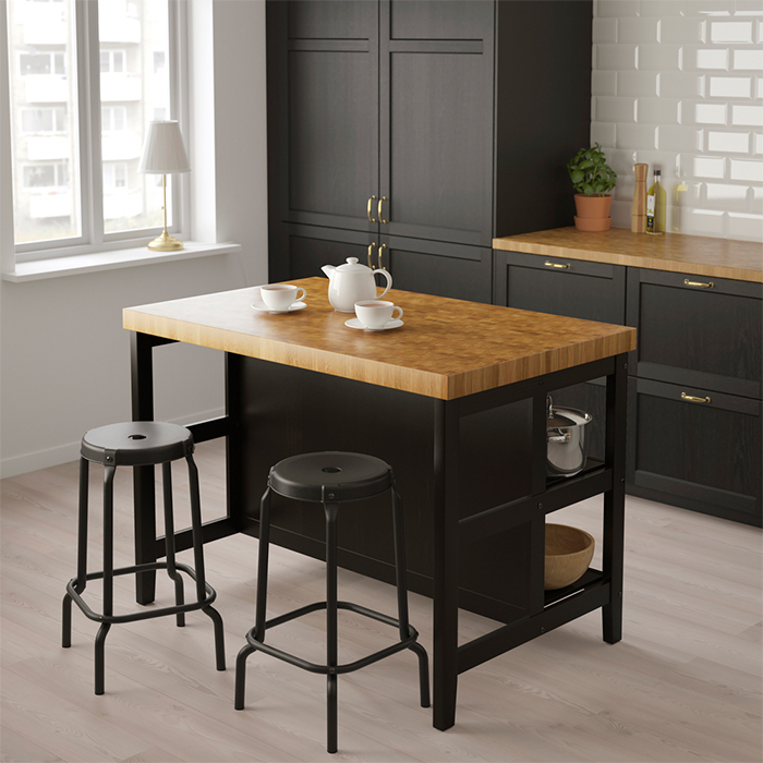 Traditional-style kitchen with a central island featuring a black base and oak wood countertop, two tall stools, and a tea set on top.