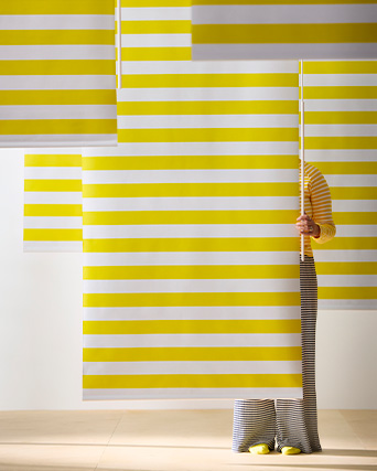 Person hidden behind yellow and white horizontal striped blinds