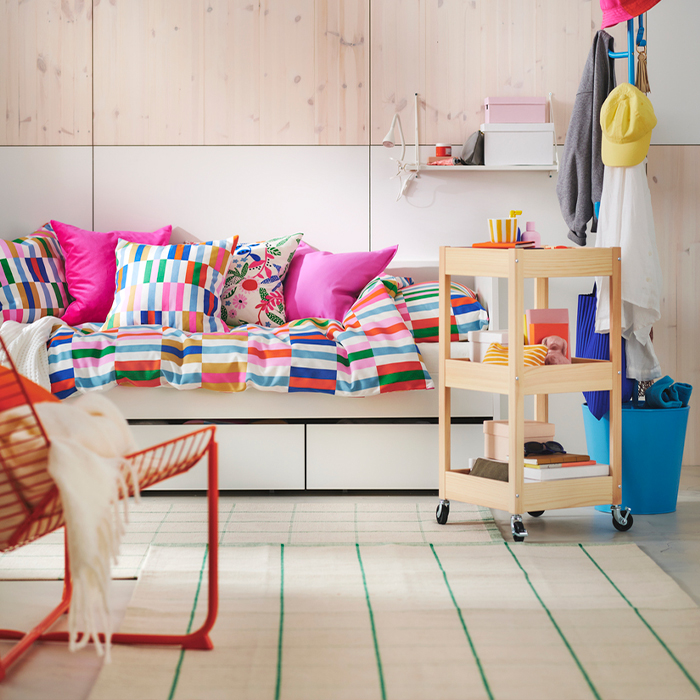 Youth bedroom with white daybed, colorful striped bedding and assorted cushions.
