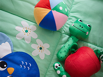 Various soft animal plush toys on a baby quilt.