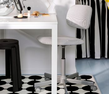 White and gray office chair, black stool, and black/white graphic rug. Modern space.