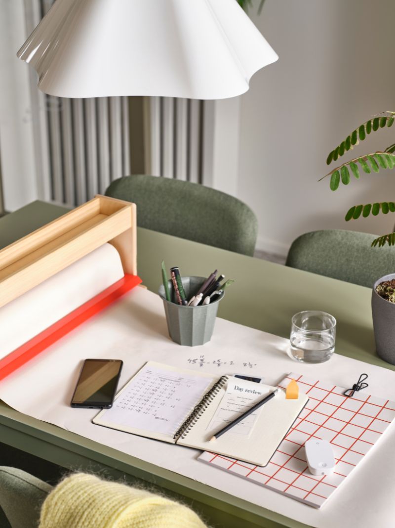 An organized desk with a green table, white lamp, and warm neutral colors. Perfect for work or study.