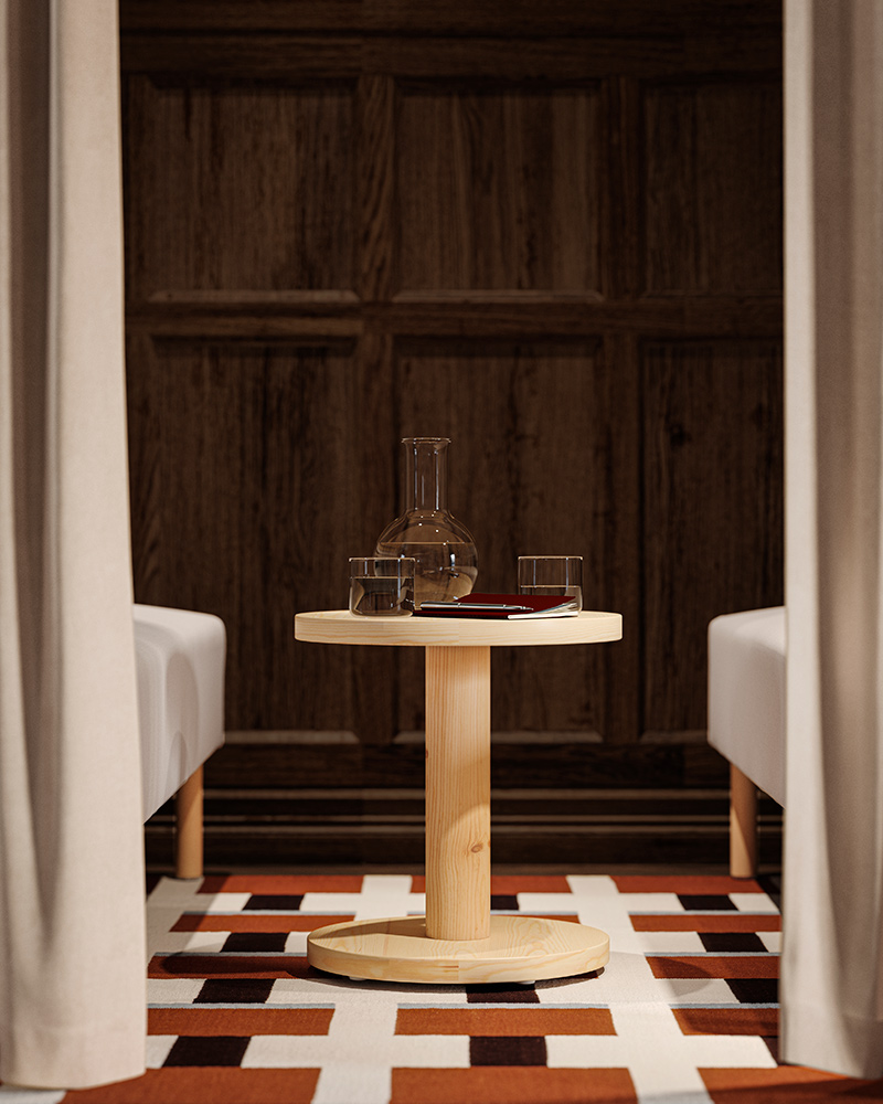 A close-up of a break room with two LILLEHEM sofas, a pine sidetable in the centre, positioned on a geometric patterned rug.