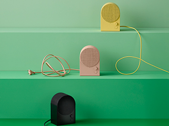 Altavoces portátiles IKEA en varios colores sobre estantes verdes. Sonido y diseño para cualquier rincón de tu hogar.