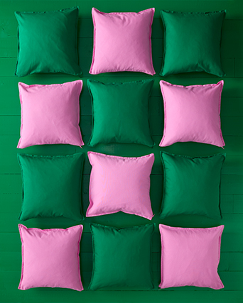 Cojines decorativos IKEA en tonos verdes y rosas sobre fondo verde. Aportando color y textura a tu espacio de forma sencilla.