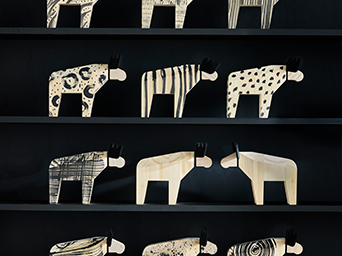 Decoración IKEA con figuras de alces de madera en estantes oscuros. Complementos únicos para personalizar tu hogar.
