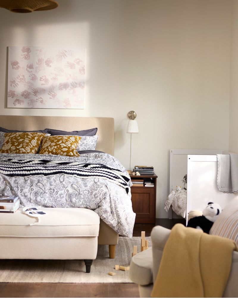 A bed covered in grey and white RODGERSIA bed linen and two cushions in IDALINNEA covers next to a children’s bed.