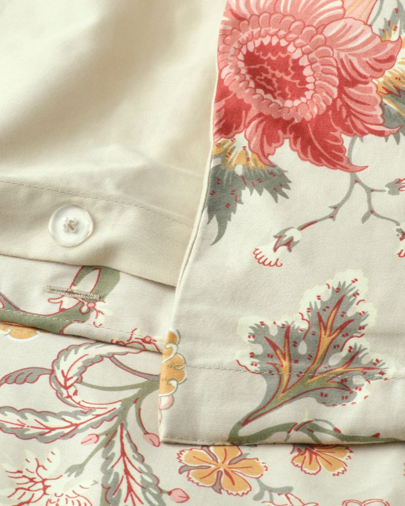 A close up image showing the edges and buttons of light grey beige/mutlicolour NÄSSELKLOCKA bed linen.
