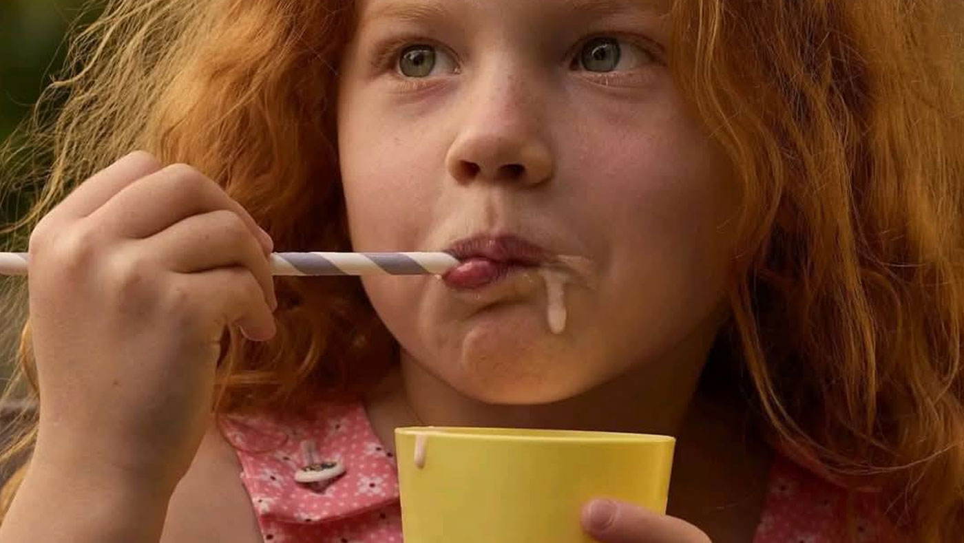 niña pelirroja comiendo en un vaso amarillo