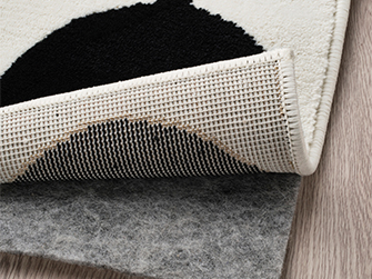 Detail of a black and white patterned rug, showing the non-slip backing. Safety and style for your floor.