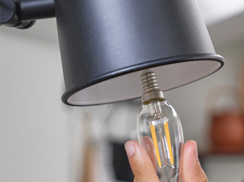 someone putting a light bulb in a lamp