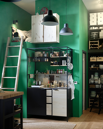Vista de una cocina en un espacio pequeño con paredes verdes. Incluye una cama en altillo, un mueble de cocina modular y un estante.