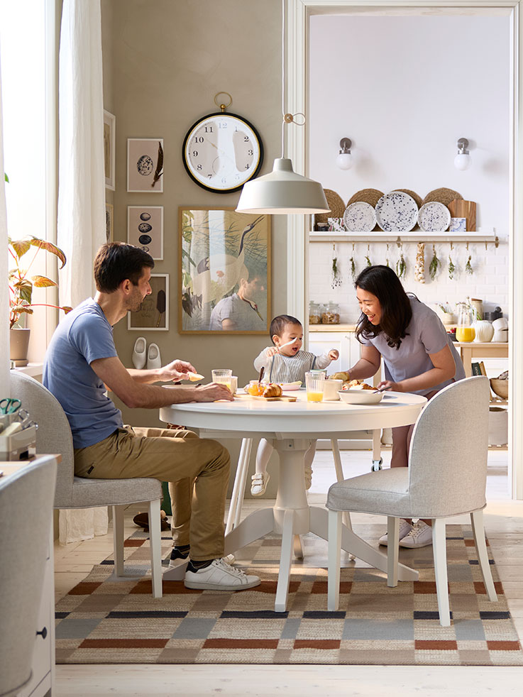 El comedor cuenta con una mesa extensible ROSENTORP blanca y dos sillas, con vistas a la cocina al fondo.