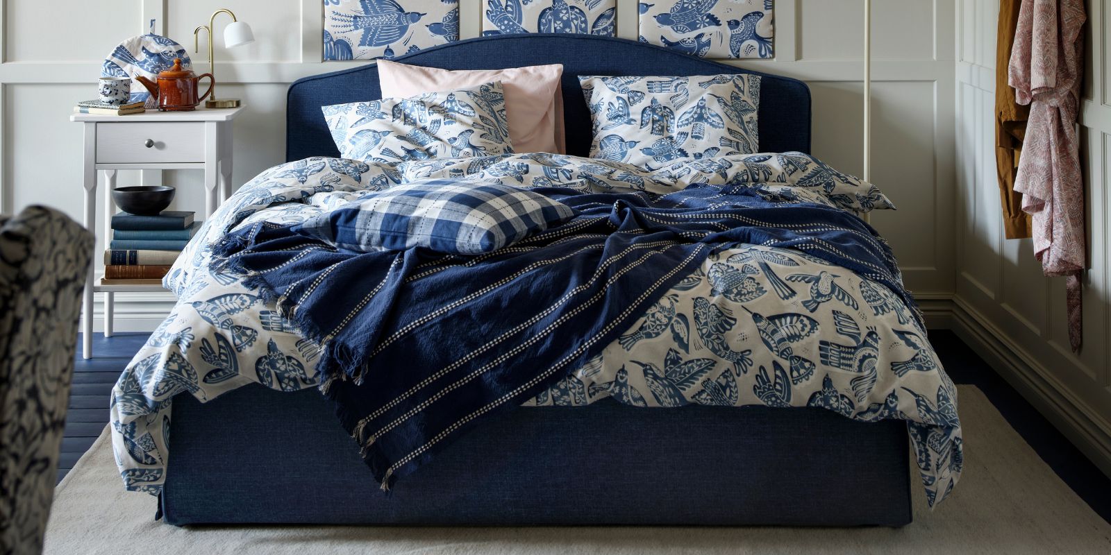 Una estructura de cama tapizada RAMNEFJÄLL azul oscuro junto con un juego de funda nórdica y fundas de almohada BITTERSÖTA y tela precortada.