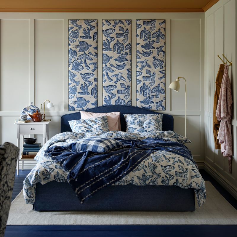 Una estructura de cama tapizada RAMNEFJÄLL azul oscuro junto con un juego de funda nórdica y fundas de almohada BITTERSÖTA y tela precortada.