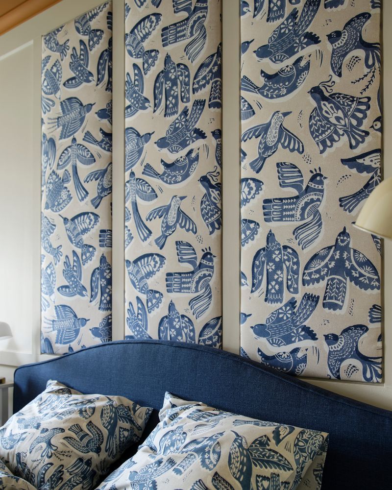 Un juego de funda nórdica y fundas de almohada BITTERSÖTA en gris/azul claro sobre una cama, debajo de paneles de pared hechos con tela precortada BITTERSÖTA.