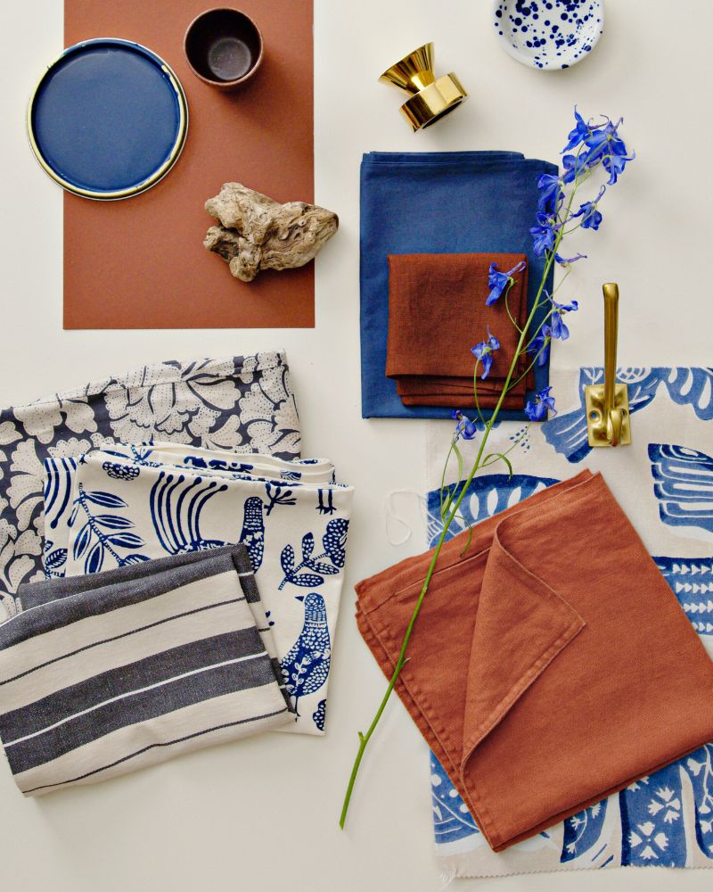 Una muestra de tela precortada BITTERSÖTA en beige y azul, exhibida junto a varios artículos decorativos y textiles.